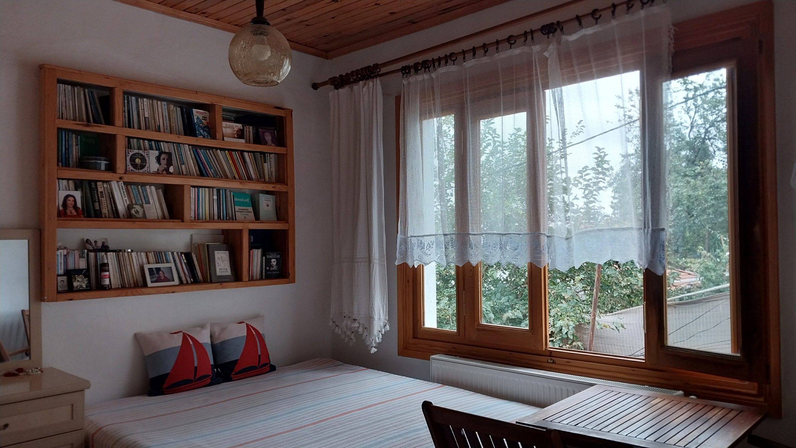 Chambre cosy avec bibliothèque bois et grandes fenêtres