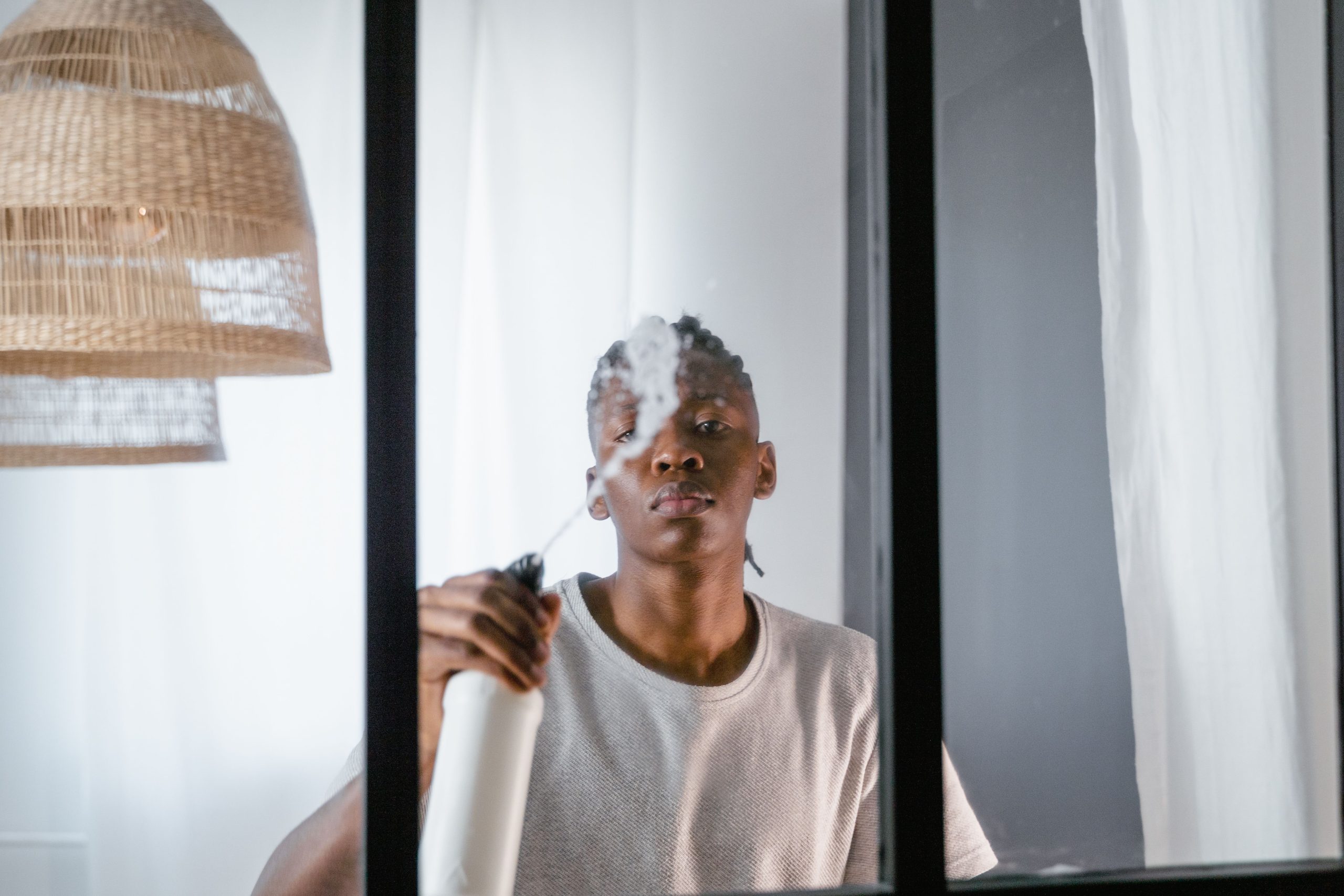 Jeune homme nettoyant une vitre au spray